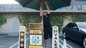 A parking lot valet opens his umbrella