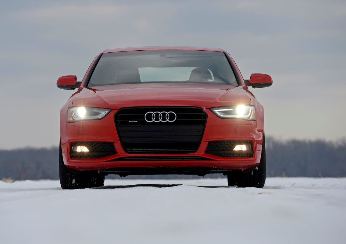 A red 2015 Audi A4 luxury compact executive car model driving on snow in Northampton, Massachusetts