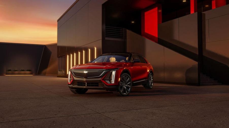 A red 2024 Cadillac Lyriq electric full-size luxury SUV model parked outside a luxury building at sunset