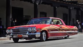 A red customized 1962 Chevy Impala lowrider model driving in a parade in Santa Fe, New Mexico