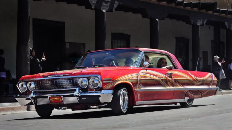 A red customized 1962 Chevy Impala lowrider model driving in a parade in Santa Fe, New Mexico