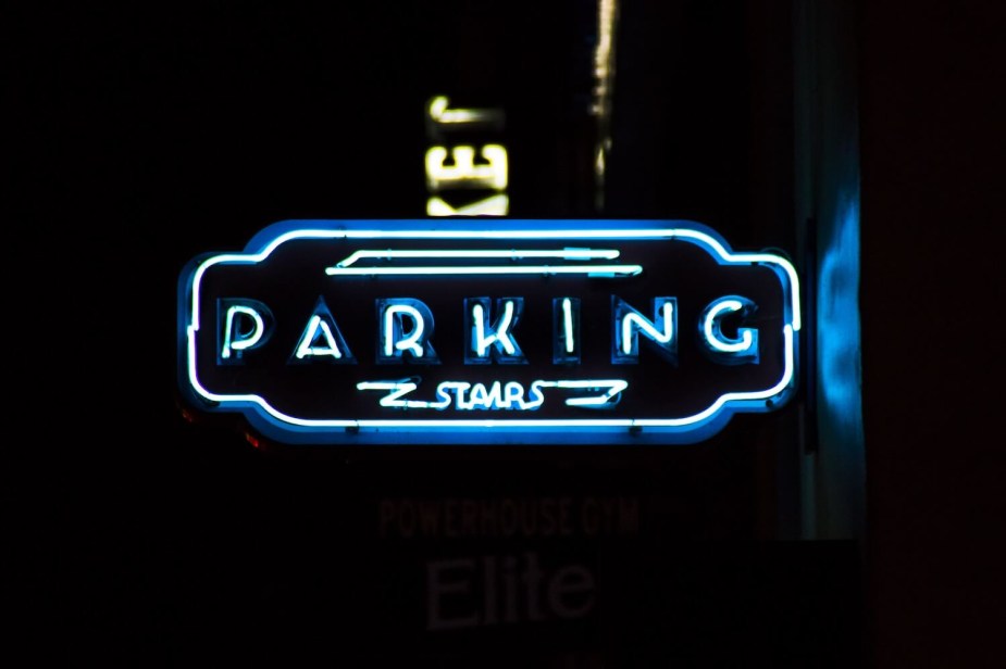 A blue neon "Parking" sign hung above a garage, the black night sky visible in the background.