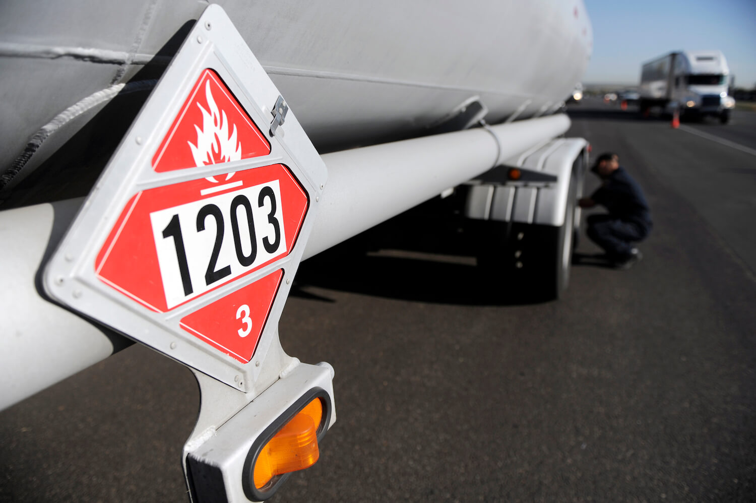 A bright red hazmat placard warns of flammable hazardous materials aboard a semi-truck trailer.