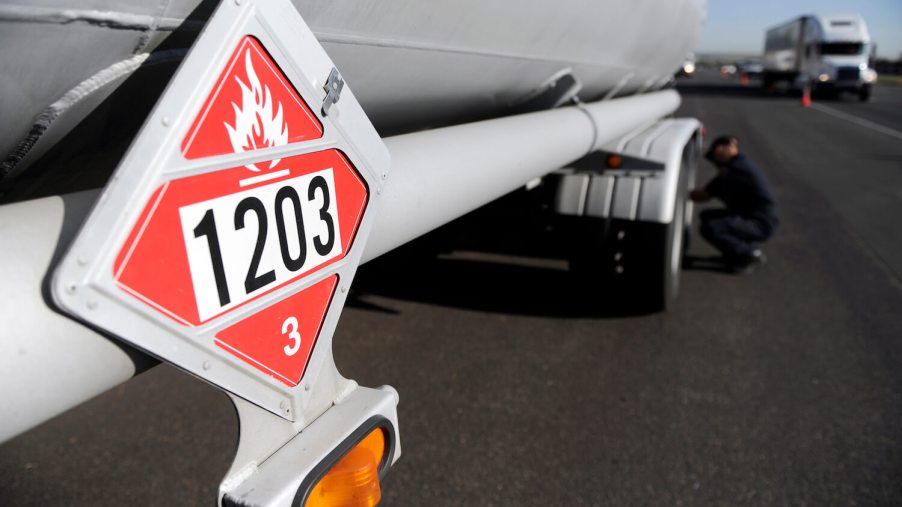 A bright red hazmat placard warns of flammable hazardous materials aboard a semi-truck trailer.