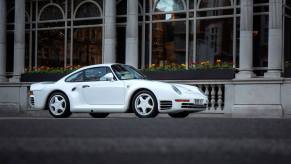 A white Porsche 959 sports car coupe rally model parked in front of the Connaught Hotel in Mayfair, London