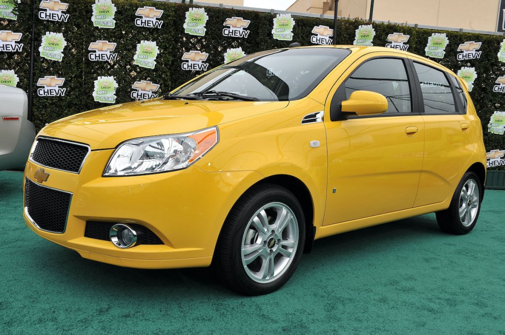 A yellow Chevy Aveo at a car show