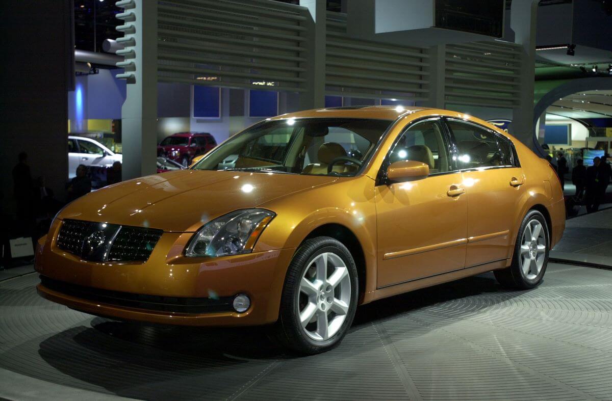 A yellow 2004 Nissan Maxima full-size sedan model on display at the 2003 North American International Auto Show