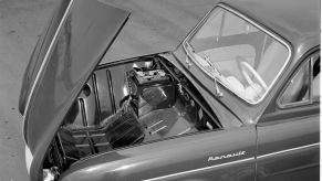 A black and white photo of an imported 1956 Renault Dauphine four-doo coupe model with a clamshell hood