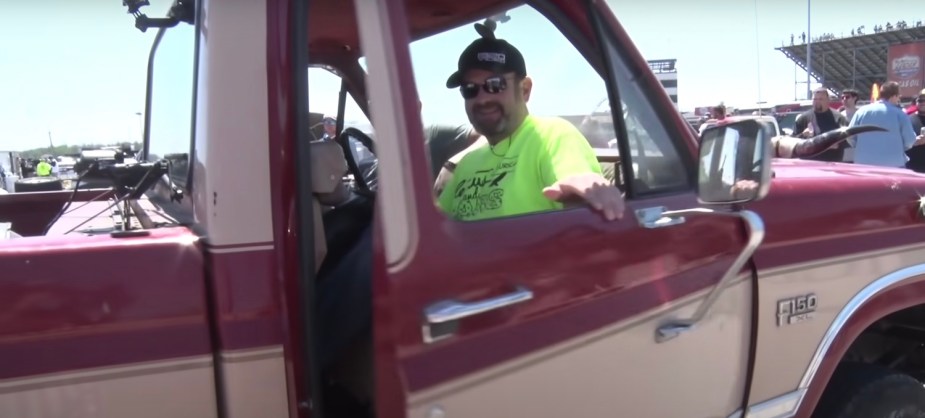 A man climbs into the backward cab of a modified Ford F-150 pickup truck.