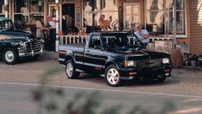 A 1991 1991 GMC Syclone half-ton pickup truck model parked on gravel outside a patio shop