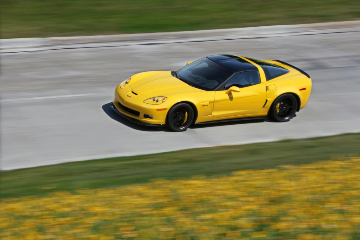 A bright yellow 2013 C6 Corvette Z06 drives on a track.