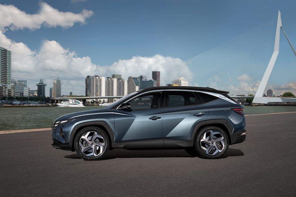 A steel-blue 2018 Hyundai Tucson overlooks water and a city skyline