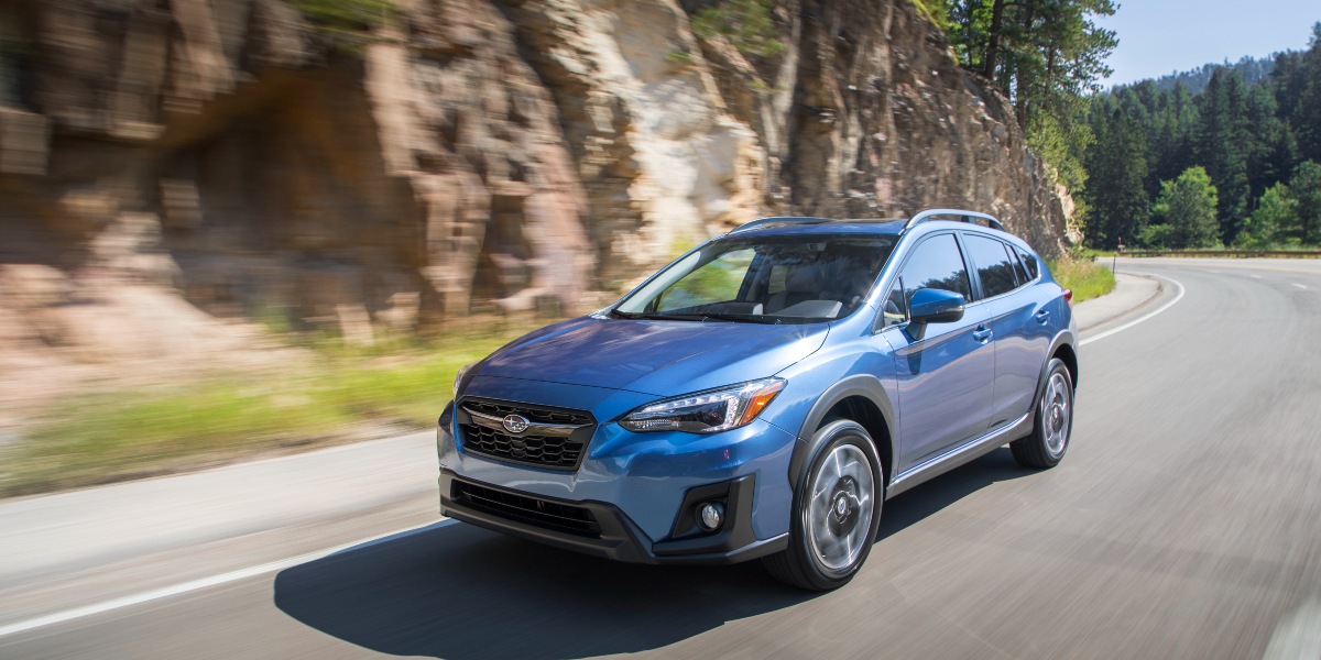 A blue 2019 Subaru Crosstrek subcompact SUV is driving on the road. 