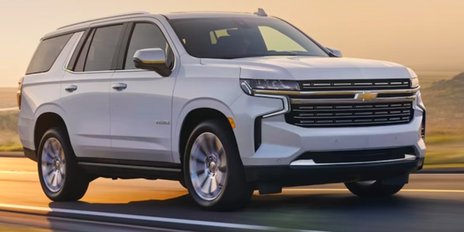 A white 2023 Chevy Tahoe full-size SUV is driving on the road. 