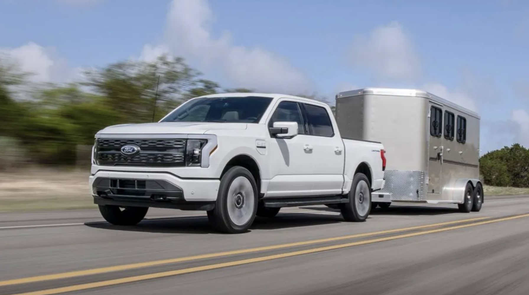 The 2023 Ford F-150 Lightning towing a trailer on the road