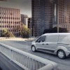 A white 2023 Ford Transit Connect compact panel van commercial vehicle driving on a city highway overpass