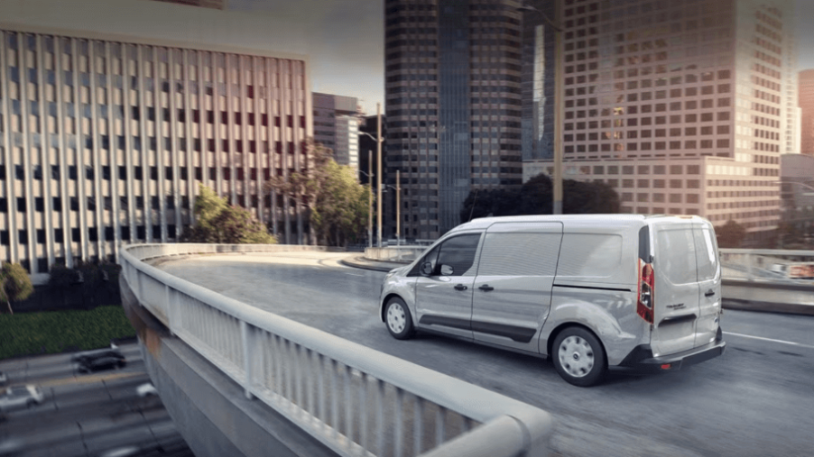 A white 2023 Ford Transit Connect compact panel van commercial vehicle driving on a city highway overpass