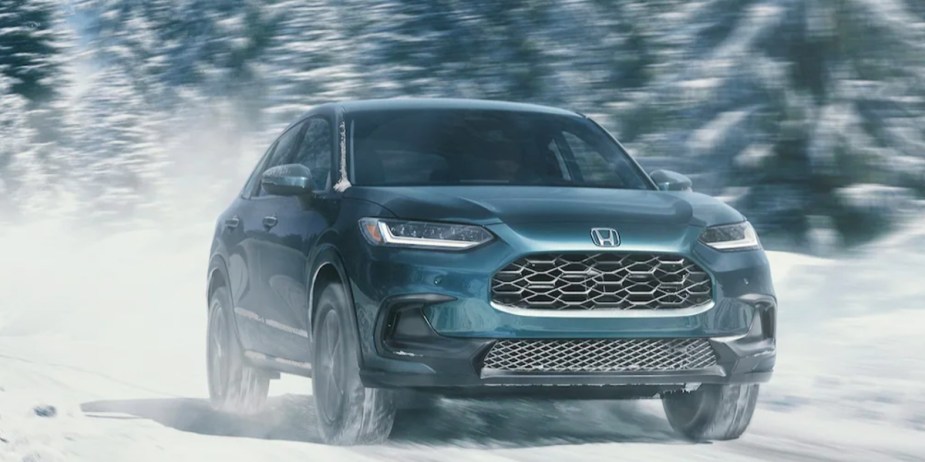 A blue 2023 Honda HR-V subcompact SUV is driving in the snow, it's one of the best leasing deals right now.