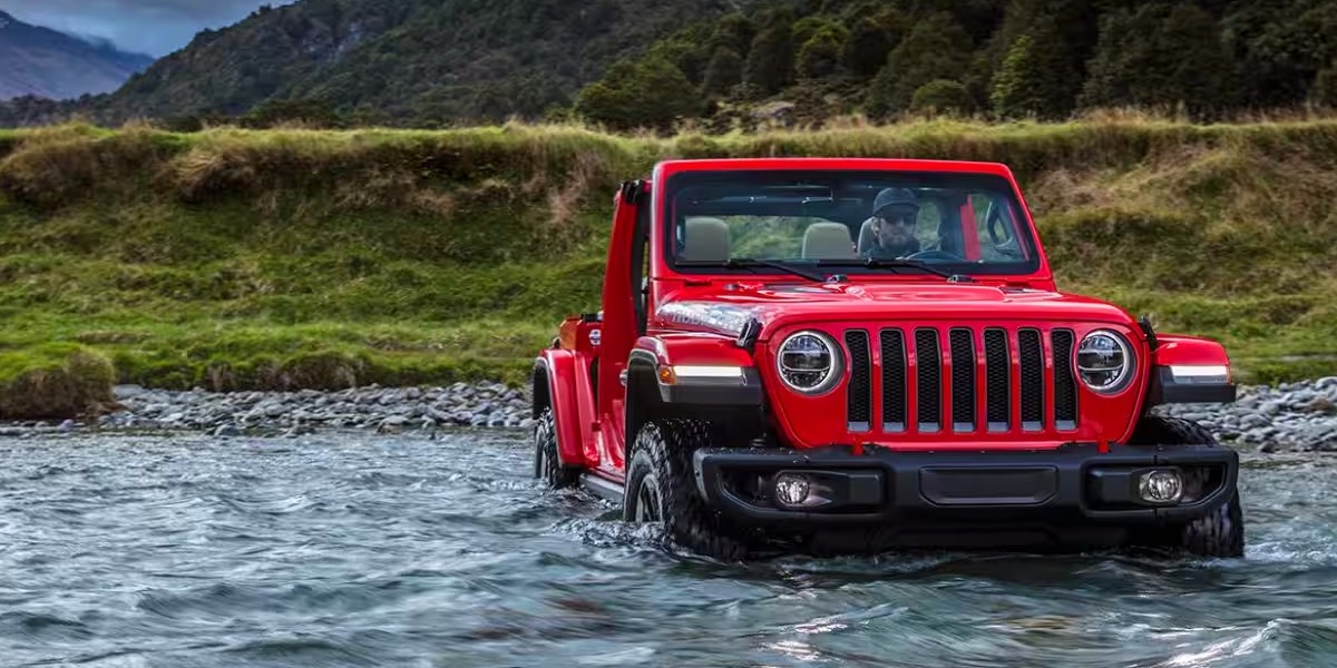 A red 2023 Jeep Wrangler Rubicon 392 is driving through water.