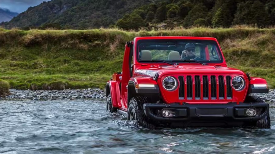 A red 2023 Jeep Wrangler Rubicon 392 is driving through water.