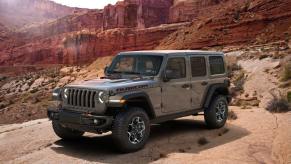 A 2023 Jeep Wrangler Rubicon off-road SUV model parked on a rocky platform near orange cliffs and canyons