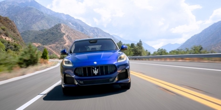 A blue 2023 Maserati Grecale small luxury SUV is driving on the road.  