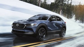 A blue 2023 Mazda CX-30 subcompact SUV is driving on the road.