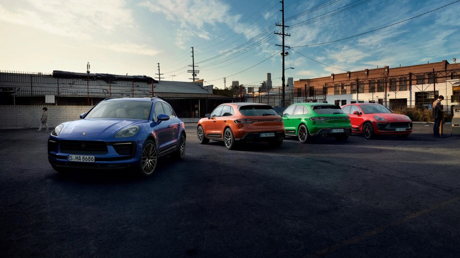 A few 2023 Porsche Macan models are lined up in a parking lot.
