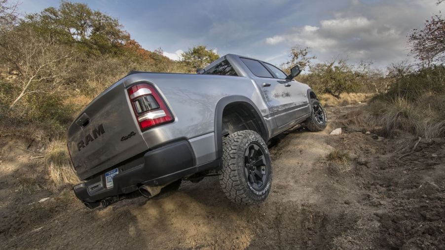 A gray Ram 1500 Rebel's suspension flexes as it navigates an off-road obstacle.