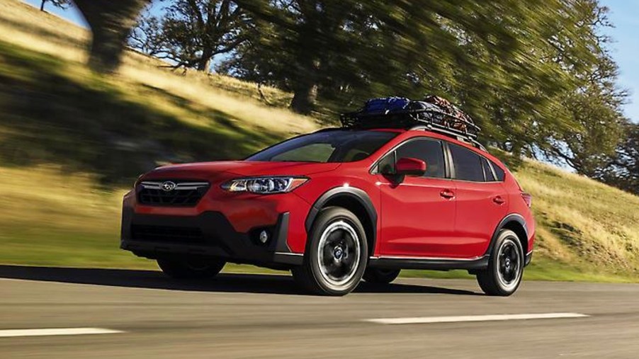A red 2023 Subaru Crosstrek subcompact SUV is driving on the road.