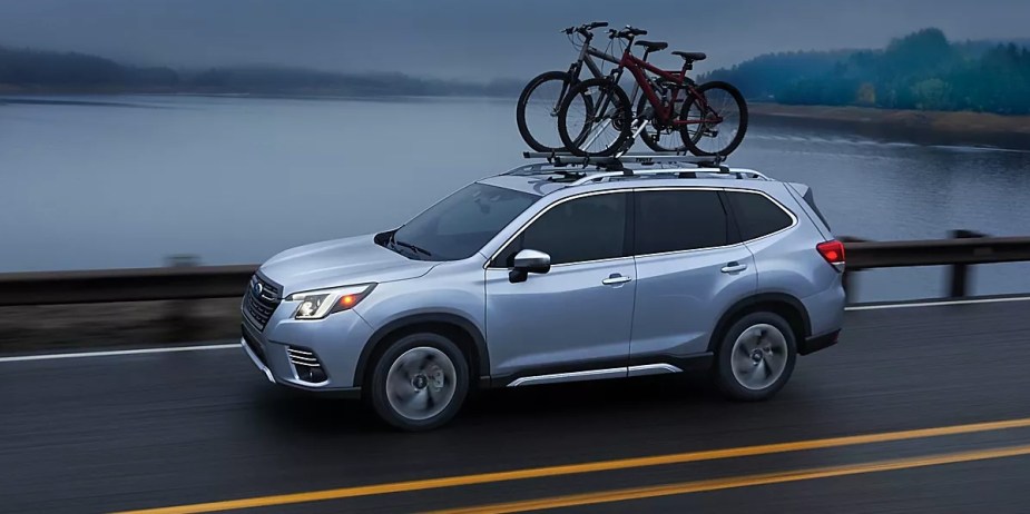 A silver 2023 Subaru Forester small SUV is driving on the road.