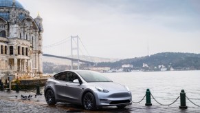 A gray 2023 Tesla Model Y is parked by the water.