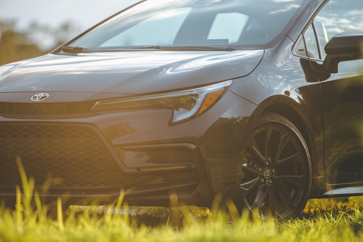 2023 Toyota Corolla close up view of the front quarter and front driver's side wheel in a sunny field of green grass. 