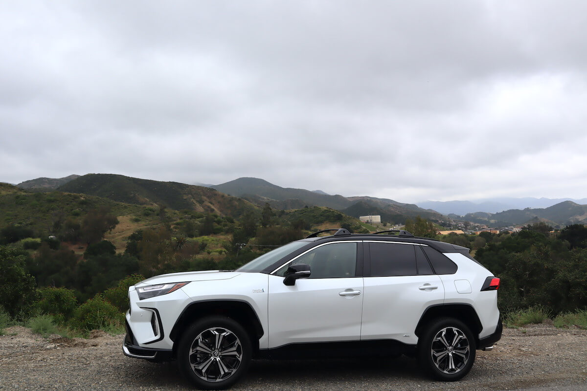 A white 2023 Toyota RAV4 Prime side view with the mountains in the background