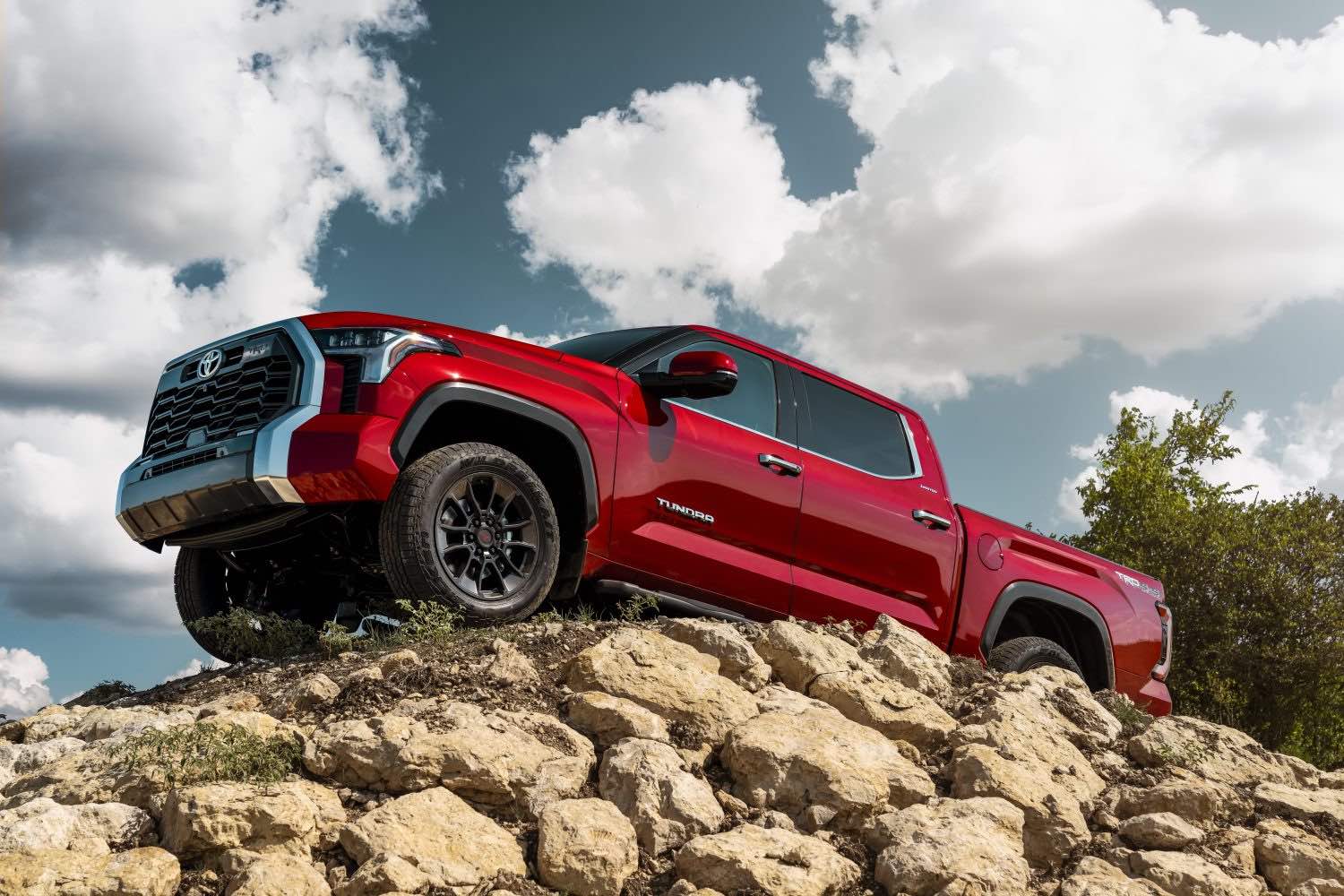 A red 2023 Toyota Tundra pickup truck parked atop a rock pile.