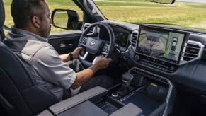 Man driving a 2023 Toyota Tundra platinum, its infotainment screen on trailering mode.