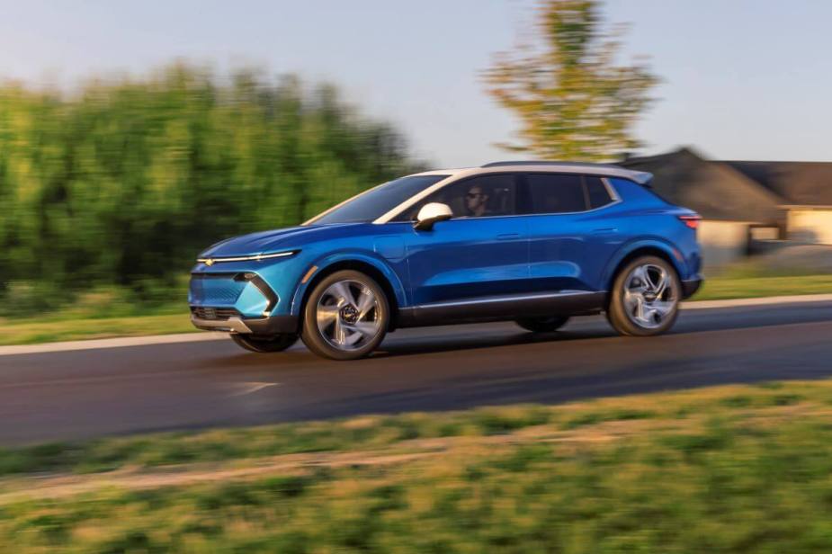 A side profile shot of a blue 2024 Chevy Equinox EV 3LT compact SUV model driving with a blurred background