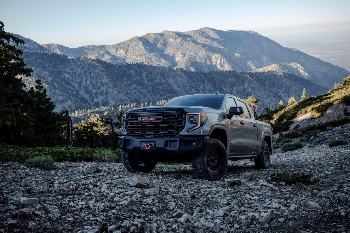 A 2024 GMC Sierra 1500 AT4X AEV Edition full-size pickup truck model parked on gravel in a forest mountain