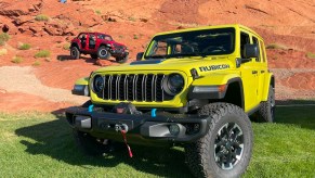 Two 2024 Jeep Wrangler models off-roading over rocks