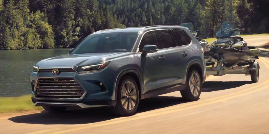 A blue 2024 Toyota Grand Highlander midsize three-row SUV is towing a jet ski. 