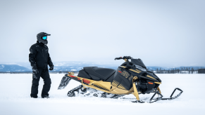 2023 Yamaha SRX snowmobile in snow with rider standing next to it