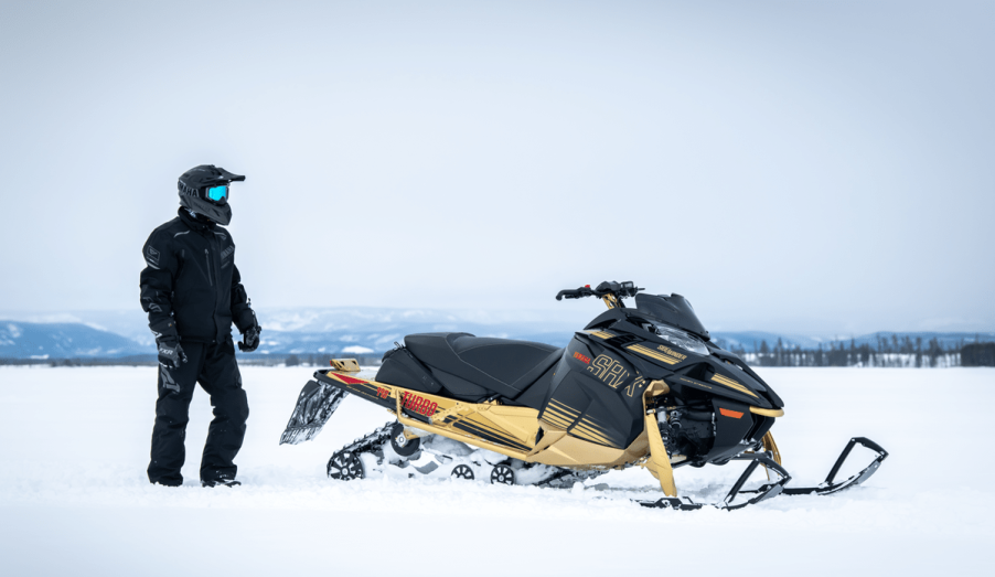 2023 Yamaha SRX snowmobile in snow with rider standing next to it