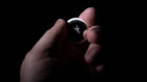 A person holds an Apple AirTag in the dark.