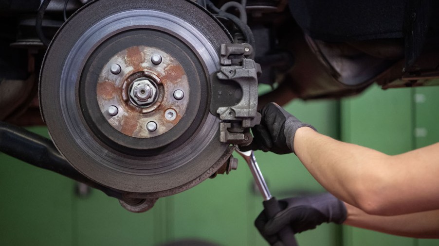 A car mechanic changes the brake disc of a Range Rover Evoque in a garage.