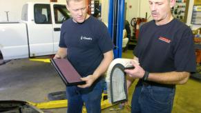 Two mechanics ready to change the air filter on a car.