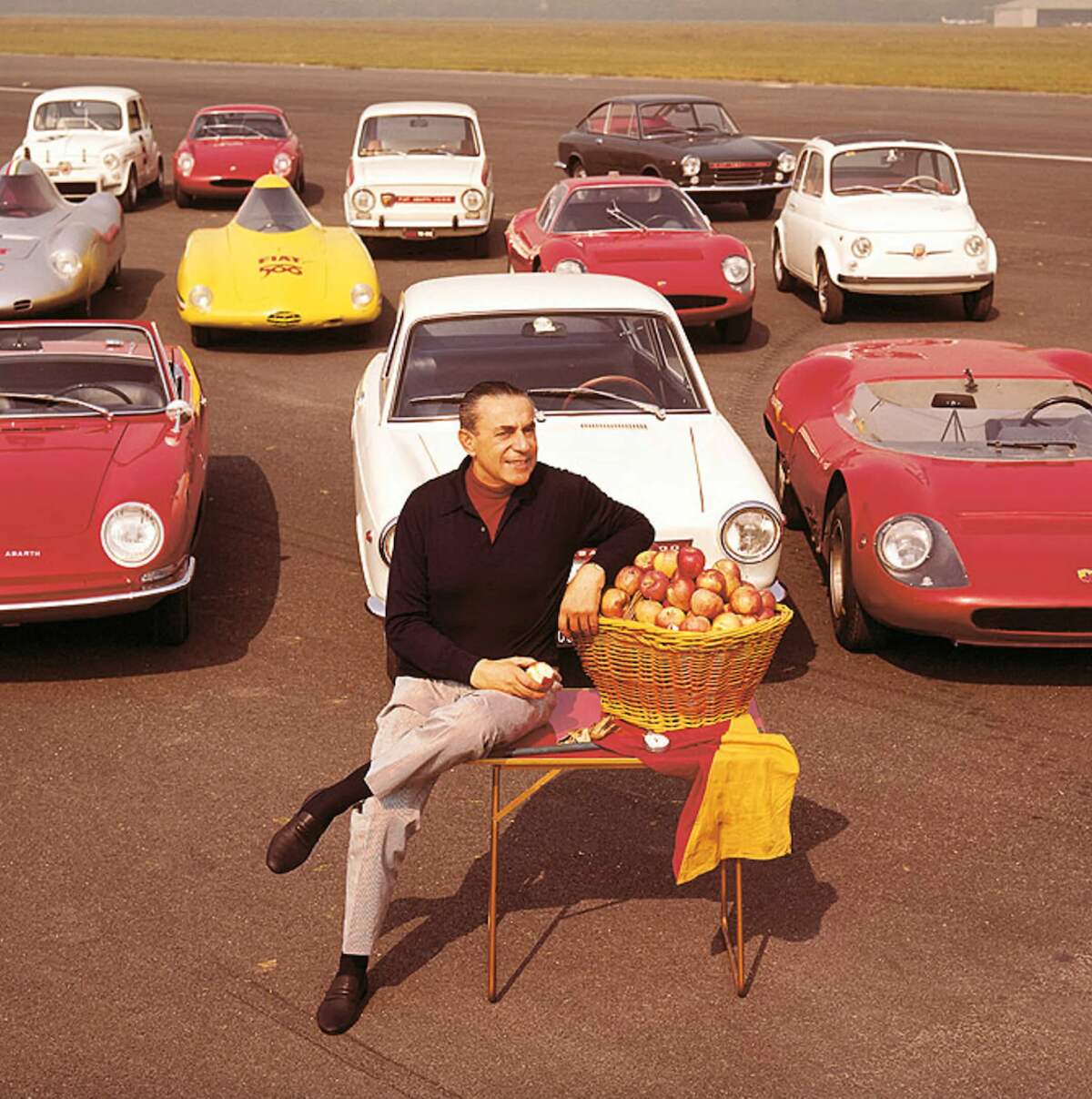 Carlo Abarth sitting in front a collection of cars he designed.