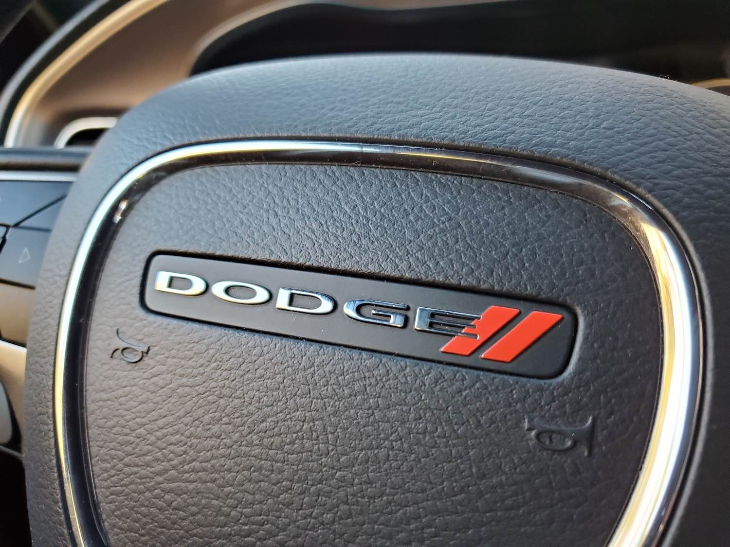 Closeup of the Dodge logo on the steering wheel of a Charger or Challenger car.