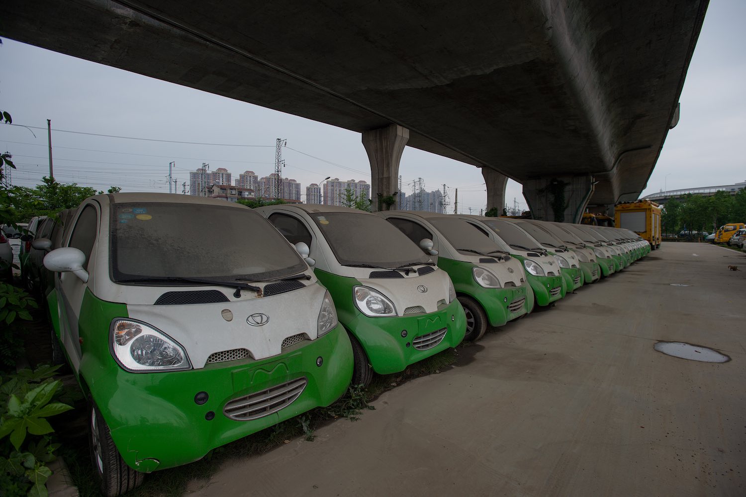 A row of unused electric vehicles (EVs) parked under a bridge in China have lithium-ion battery packs.