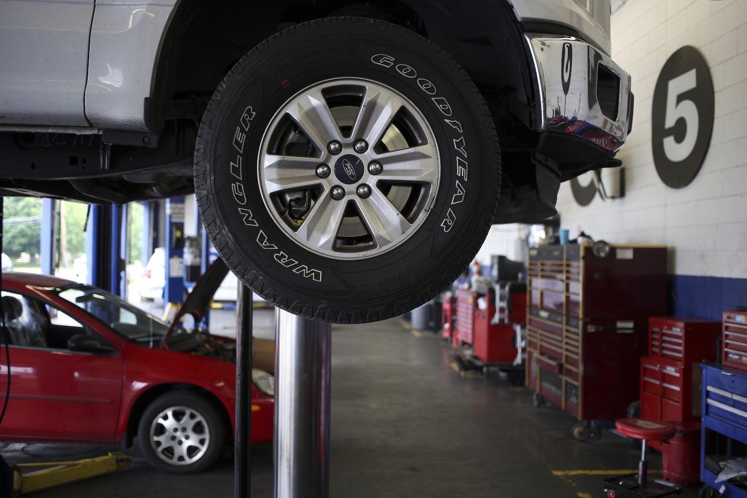 Closeup of the Ford logo on the wheel of an F-150 pickup truck on the lift at a shop.