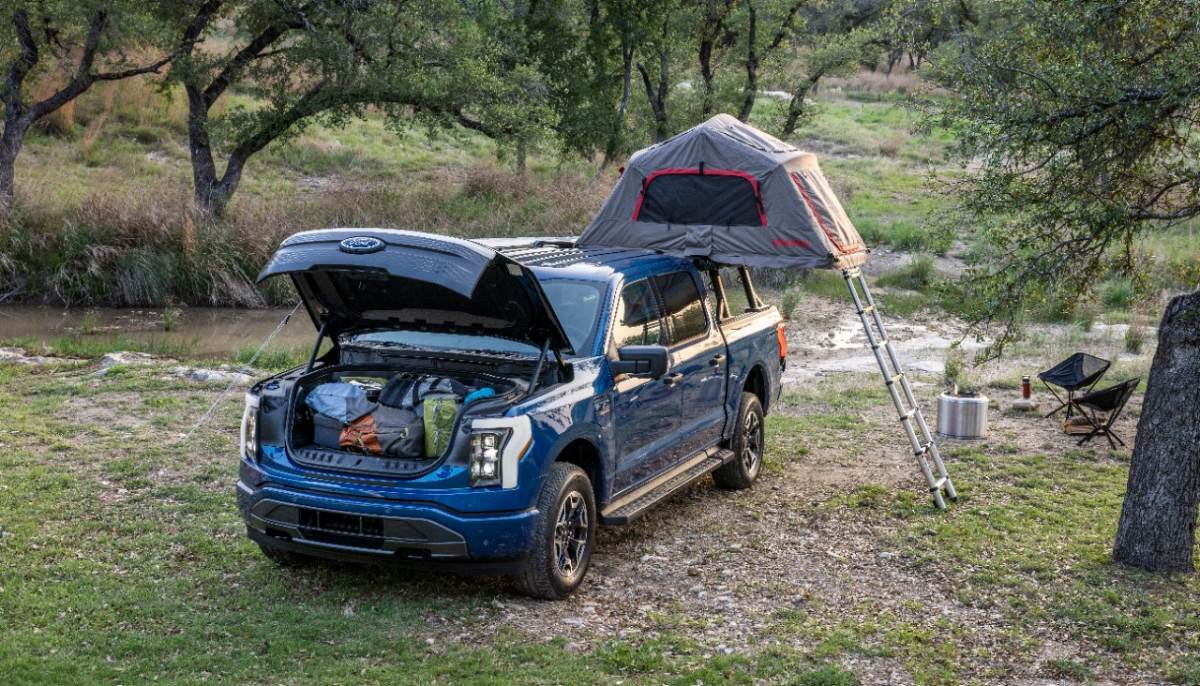 A Ford F-150 Lightning camping with its frunk open.